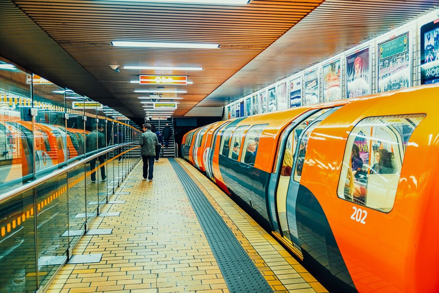 Un tren portocaliu trece de-a lungul unui peron din interiorul metroului Glasgow din Scotia.