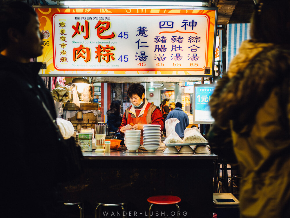 Un bucatar sta in spatele standului ei de mancare stradala din Taipei, Taiwan.