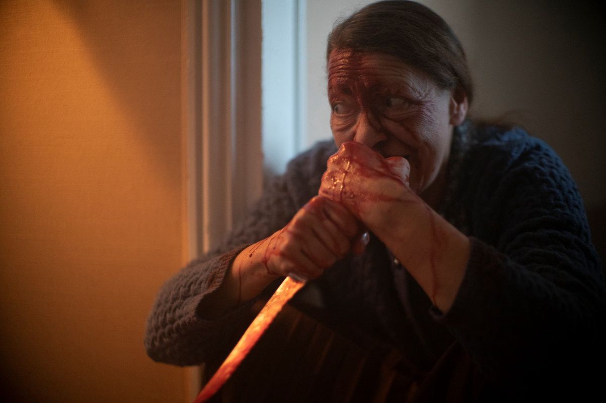 O doamna Daugeron stapanita de vrajitoare tinand un cutit si devorand carne umana in Marianne (2019).